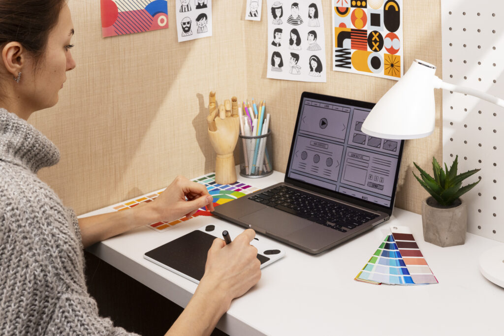 Beginner creating graphic design on a laptop with design software and color palettes on screen.